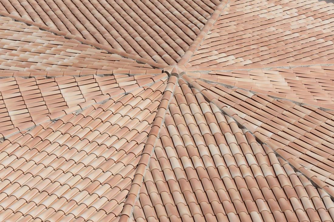 Detailed view of terracotta roof shingles forming a geometric pattern from above.